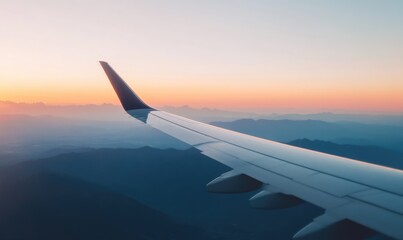 Obraz premium Airplane Wing Over a Mountainous Landscape at Sunset
