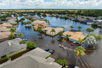 Aftermath of hurricane Debby flooding natural disaster. Boat floating on flooded street surrounded...