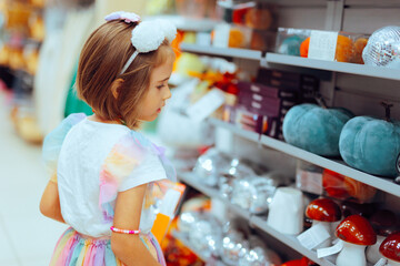 Little Girl Shopping for Halloween Decorations in a Store. Child searching for the perfect holiday decor during autumn
