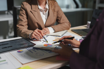 Two businesswomen are sitting at a table in a conference room, talking, discussing, meeting, financial business information. Online marketing, information, documents, laptop in modern office.
