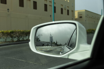 View of city street and iconic building reflected in car's side mirror