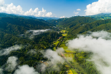 Aerial view drone shot of flowing fog waves on mountain tropical rainforest,Bird eye view image over the clouds Amazing nature background with clouds and mountain peaks