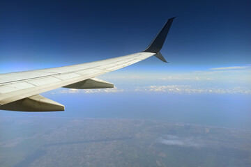 Obraz premium View through airplane window of commercial jet plane wing flying high in the sky. Air travelling concept
