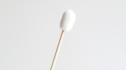 Close-up of a single cotton swab held against a plain white background, highlighting the soft tip and wooden stick during a clean-up routine