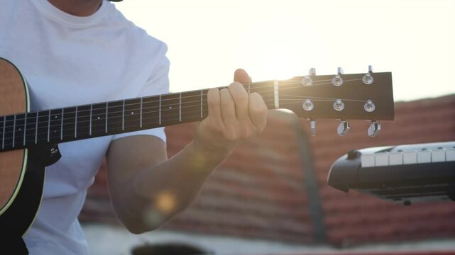 man playing acoustic guitar on a rooftop with the sunlight