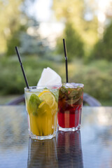 Two drinks on a table, one is orange and the other is red