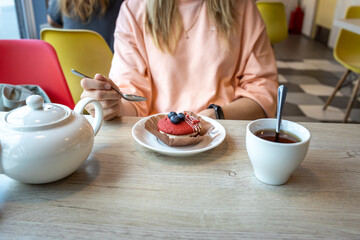 A woman is sitting at a table with a plate of dessert and a cup of tea