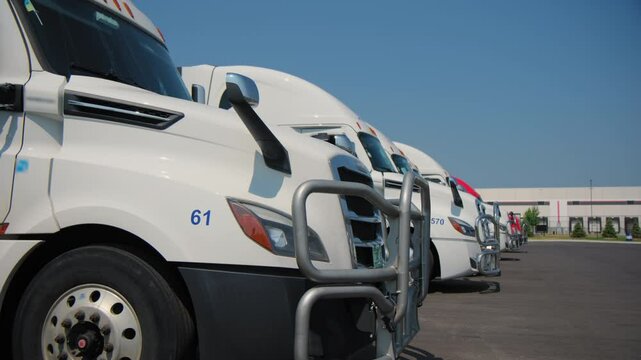Seven trucks in the parking lot near the warehouses