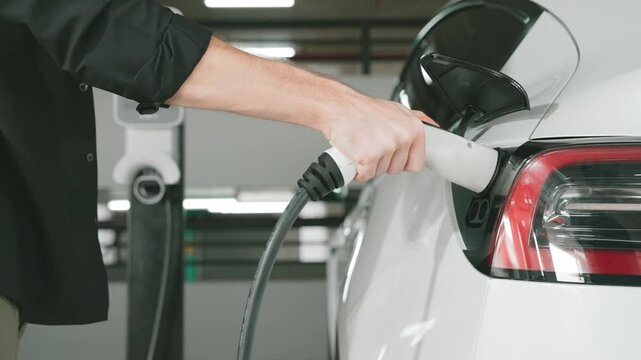Young man travel with EV electric car to shopping center parking lot charging station in downtown city urban sustainability lifestyle by green clean rechargeable energy of electric vehicle innards