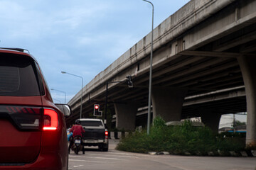 Rear side of cars dark red color on the road heading towards the goal of the trip. There is a level bridge on the side. Under blue sky.