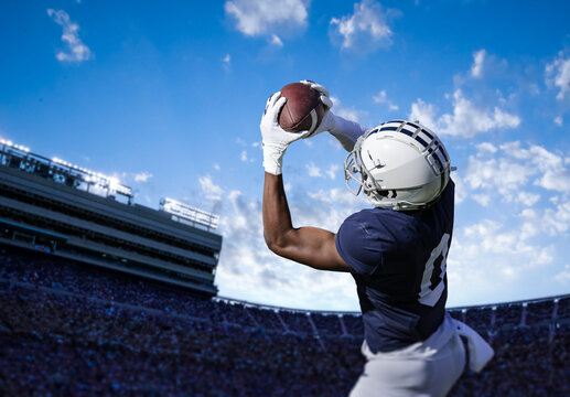 American Football Player catching a pass during a game. View from below as he tries to score a touchdown 