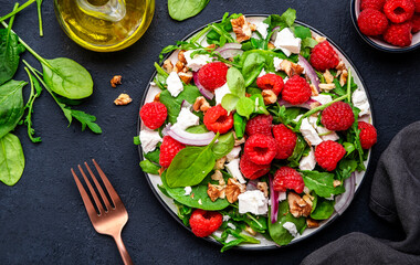 Foodie food salad with fresh raspberries, feta cheese, onion, walnuts and spinach, black background, top view