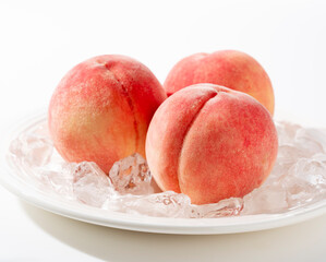 Cut peaches and ice on a plate on white background.