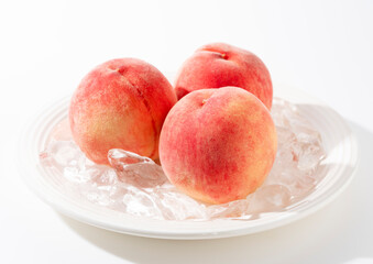 Cut peaches and ice on a plate on white background.
