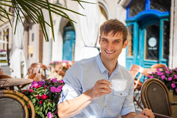 Cheerful man enjoying coffee at a Parisian cafe with flowers in spring