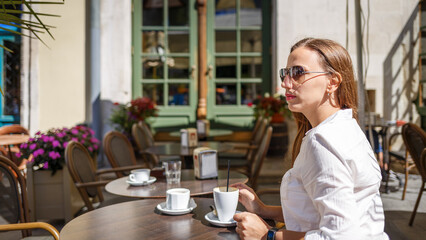 Woman enjoying coffee at an outdoor cafe on a sunny afternoon in the city