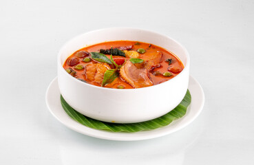A delicious bowl of spicy and flavorful curry garnished with fresh herbs, served in a white bowl on a white background.
