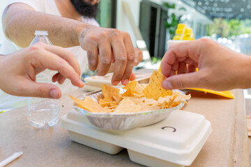 In a vibrant and lively scene, hands eagerly reach for delicious nachos, symbolizing the joy of shared moments and the lasting friendships that often develop over delightful and tasty food