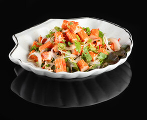 A delicious pasta salad served in a shell-shaped white dish against a black background, garnished with fresh herbs and vegetables.