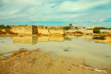 an old dilapidated village, raw clay brick. Clay-colored puddles after rain. Qeshm Island, Iran