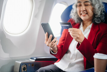  Asian seniorexecutive excels in first class, multitasking with digital tablet, laptop and...