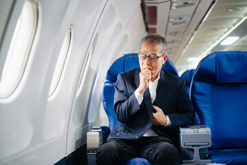 Asian senior executive excels in first class, multitasking with digital tablet, laptop and...
