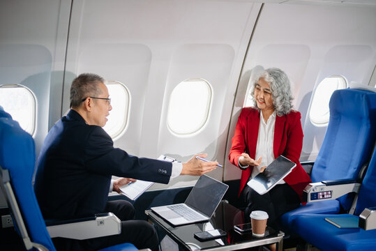 Business meeting in airplane, asian Mature businessman in private jet is talking with Mature female colleague and documents, business people flying