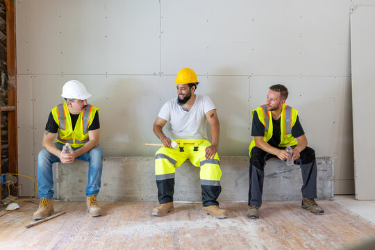 A cheerful and vibrant group of construction workers taking a welldeserved break on a bustling job site, showcasing their excellent teamwork and unwavering commitment to safety and collaboration