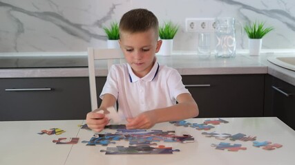 Focused boy collects puzzles at table. Hands of child assemble puzzle. Child development concept. Selective focus. Vertical image.