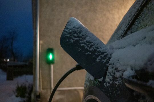 Snow covered electric car charging at night