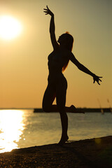 athletic woman in a bikini against the backdrop of a sunset