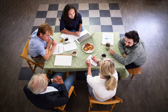 Team of business coworkers discussing strategy while sitting at desk in office during meeting