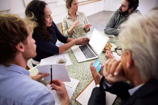 High angle view of colleagues discussing strategy while sitting at desk in office during meeting