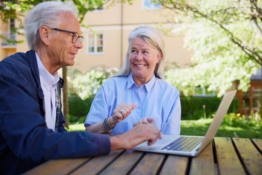 Senior man using laptop while sitting with wife in park
