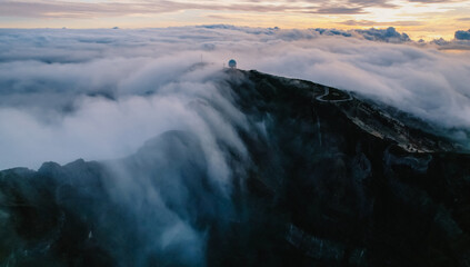 Aerial view of majestic mountain ridges at sunrise with falling fog from top of Pico do Areeiro, Madeira island, Portugal