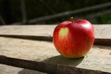 one red apple on an old wooden table