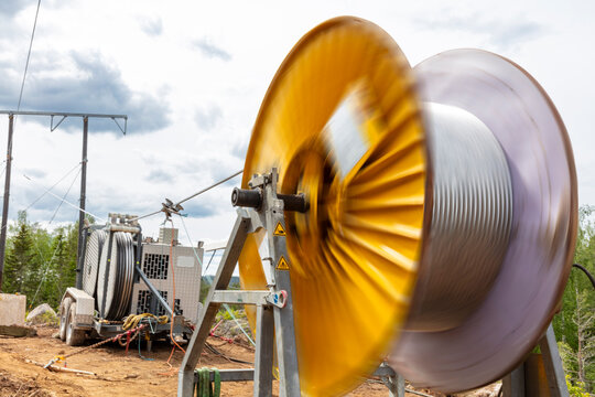 Large cable spool spinning at construction site against cloudy sky