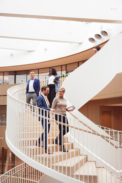 Low angle view of multiracial business colleagues moving down on spiral staircase in office