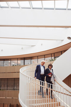 Low angle view of businessman and businesswoman moving down on spiral steps in office