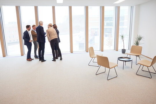 Corporate colleagues planning while standing by window in office