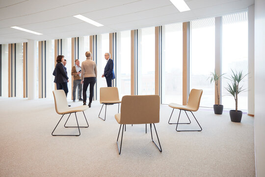 Corporate colleagues discussing while standing by window in office