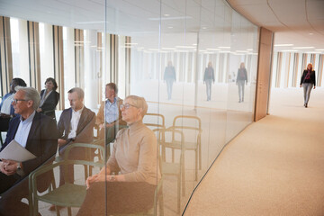 Businesswoman walking in corridor while coworkers attending seminar in office