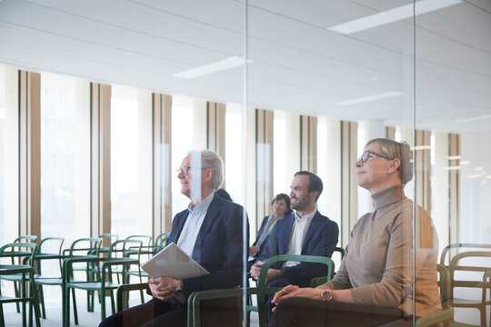 Business colleagues attending seminar seen through glass in office