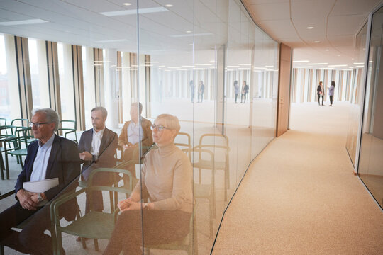 Businesswomen discussing in corridor while colleagues attending seminar in office