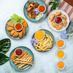 Assorted appetizers including fries and wings with various dipping sauces on a table with floral decoration.