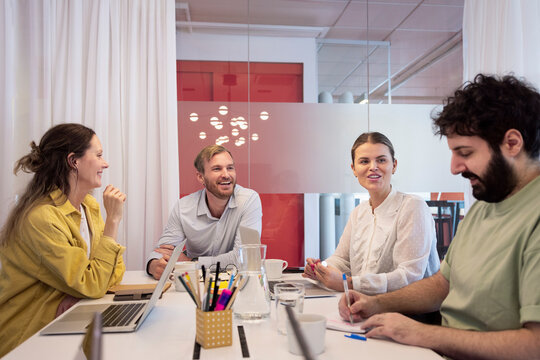 Cheerful corporate employees planning while sitting over table in office