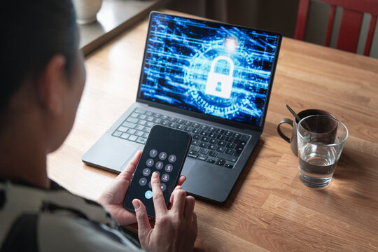 Woman dialing on smart phone with encrypted laptop on table at home