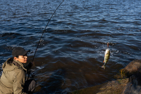 Woman fishing on lakeshore during sunny day