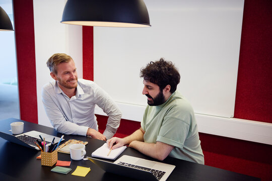 Young corporate colleagues discussing over table in office