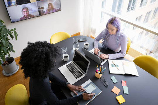 High angle view of businesswomen working on laptop during virtual meet at office